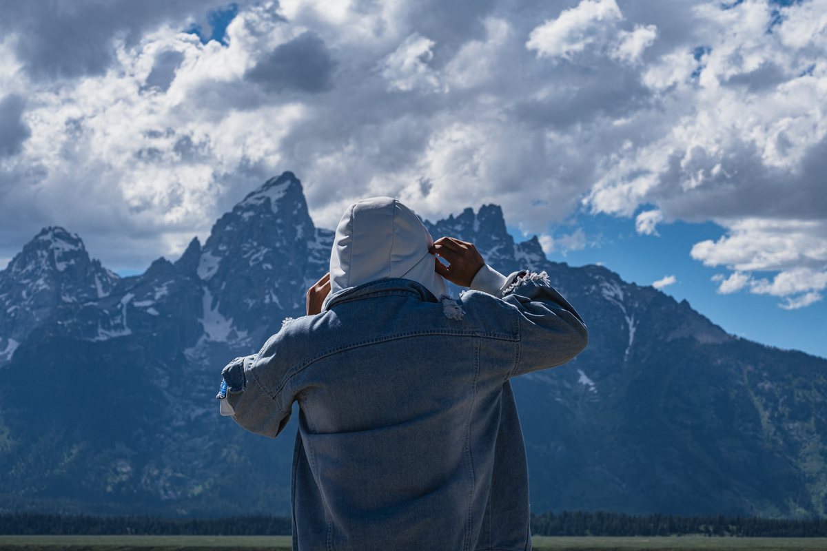 Ming Lyu, seen from behind, facing a mountain range under heavy clouds